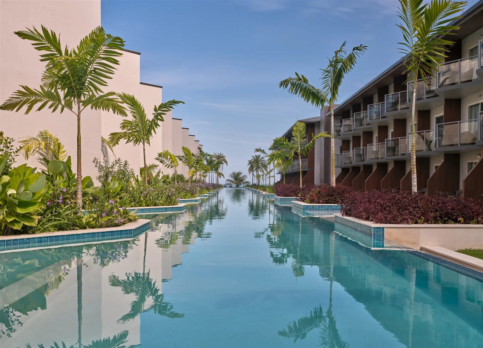 Long resort pool stretching between palm trees and hotel buildings toward the ocean at Crowne Plaza Fiji Nadi Bay.